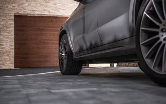 Modern Crossover Car on a Driveway in Front of House Built In Garage. Automotive Theme.